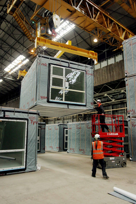 An image of a 4-sided module being lifted by a crane.